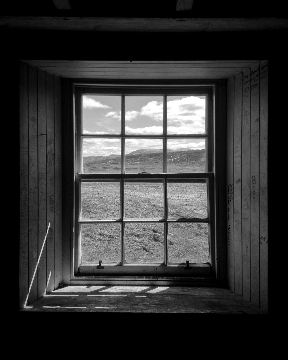 A window in a dark wooden room looking out on the moors