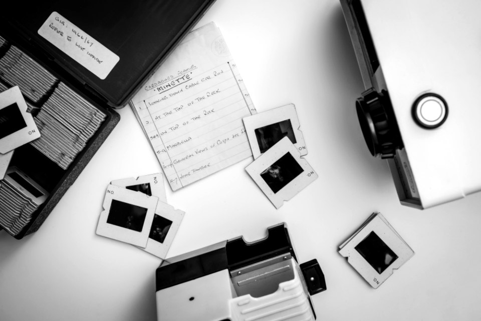 Small prints, slides and notes spread on a white table